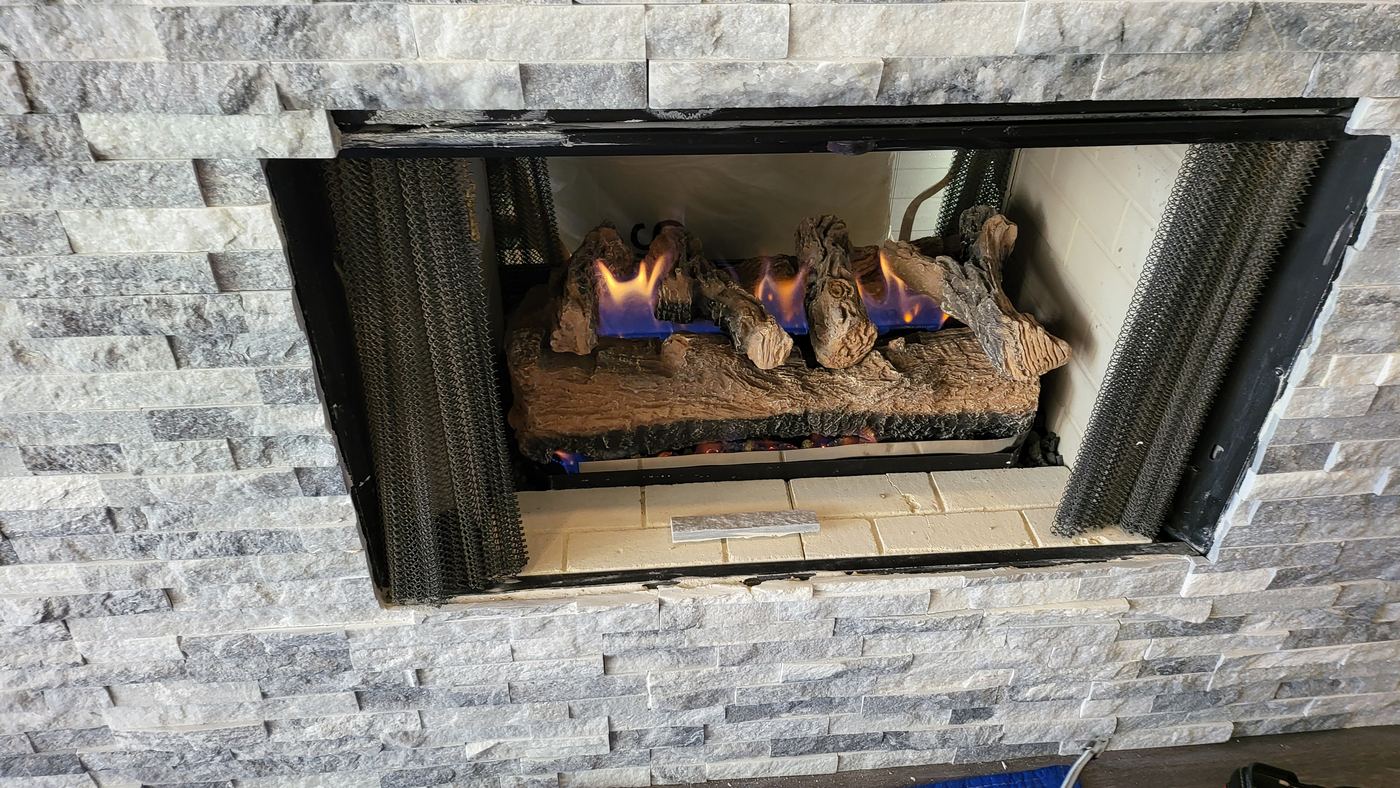 Lit gas fireplace with driftwood logs, Naples FL